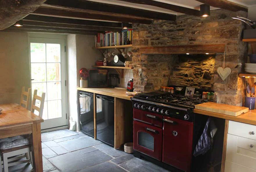 The renovated cottage kitchen, featuring the unblocked original fireplace and reclaimed slate floor.