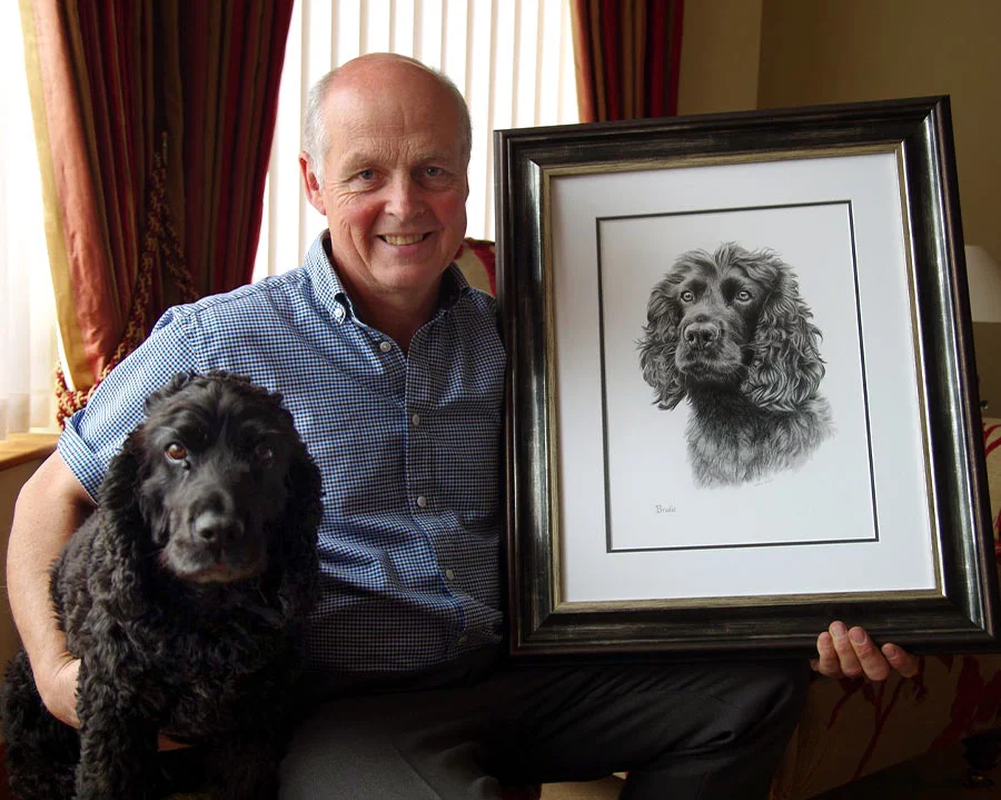 Happy client Dave with his dog Brodie and their framed pencil portrait of Brodie.